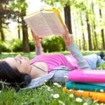 girl lying on grass and relaxing with book and music
