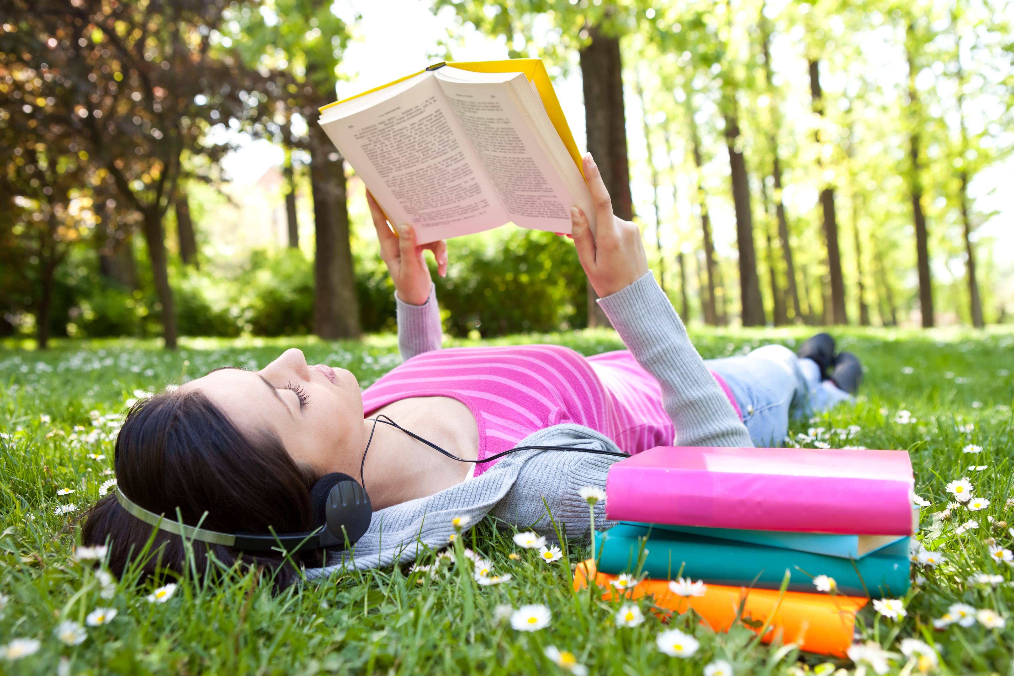 girl lying on grass and relaxing with book and music