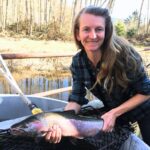 Person holds full grown salmon.