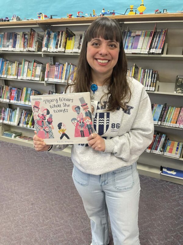 Photo of a woman with brown hair holding up a children's book