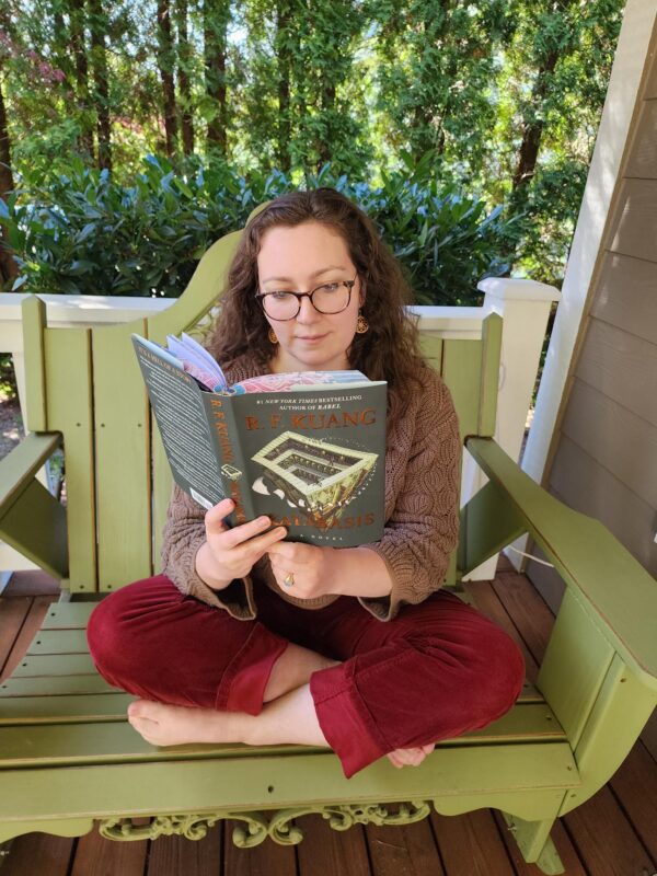 Person reading a book on an outdoor bench