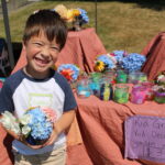Young entrepreneur selling flowers in handmade vases at Children's Craft Fair