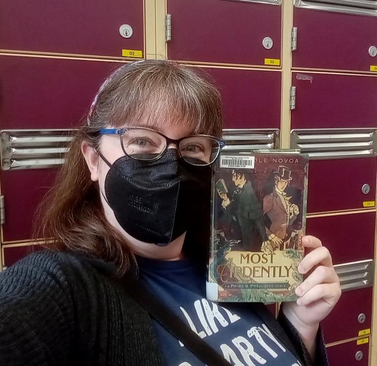 picture of a person wearing a protective face mask holding up a book