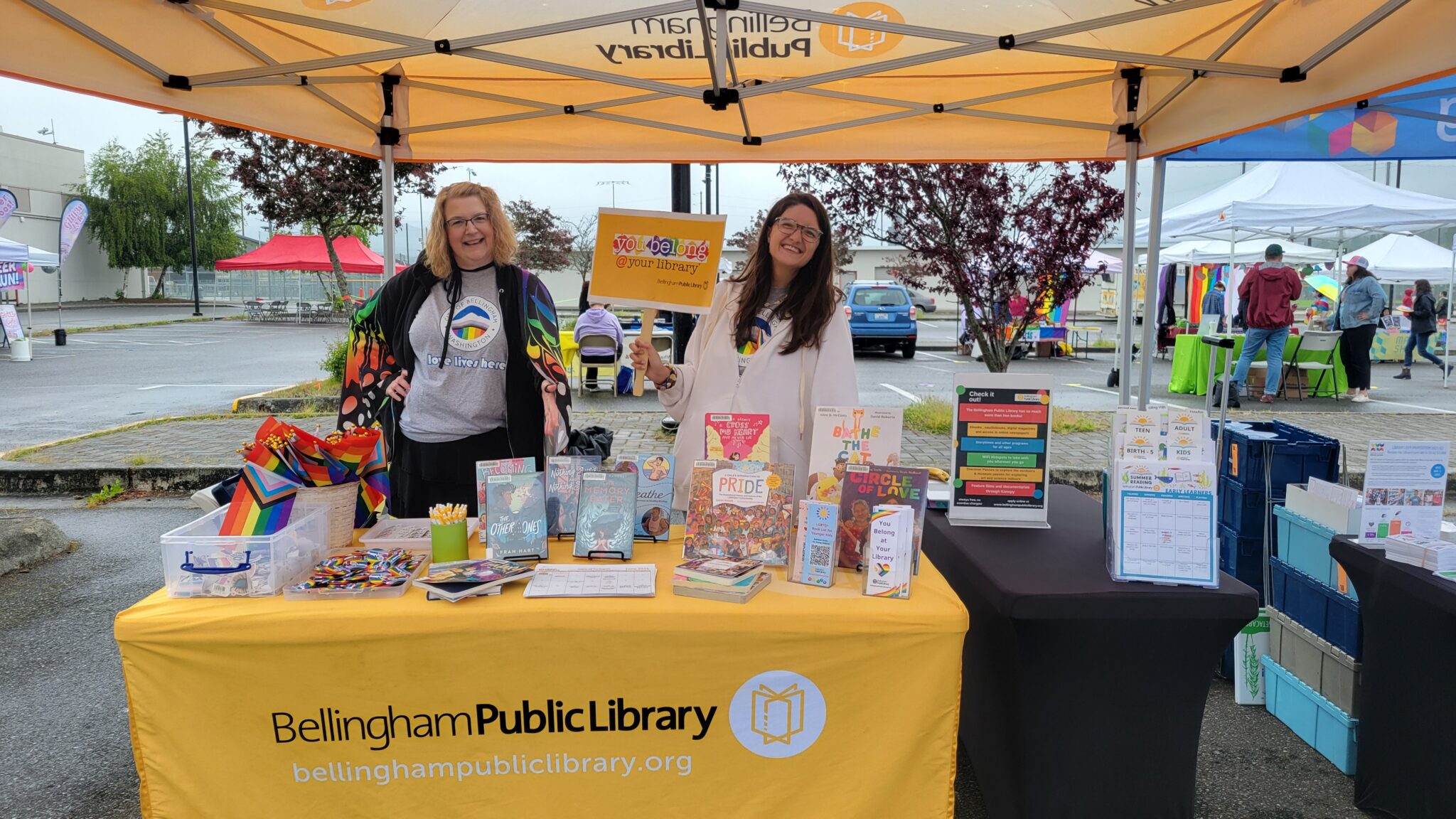 Two library staff members at a colorful booth with library materials