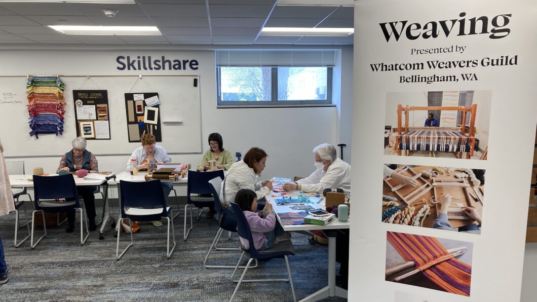 People participating in weaving activities at library