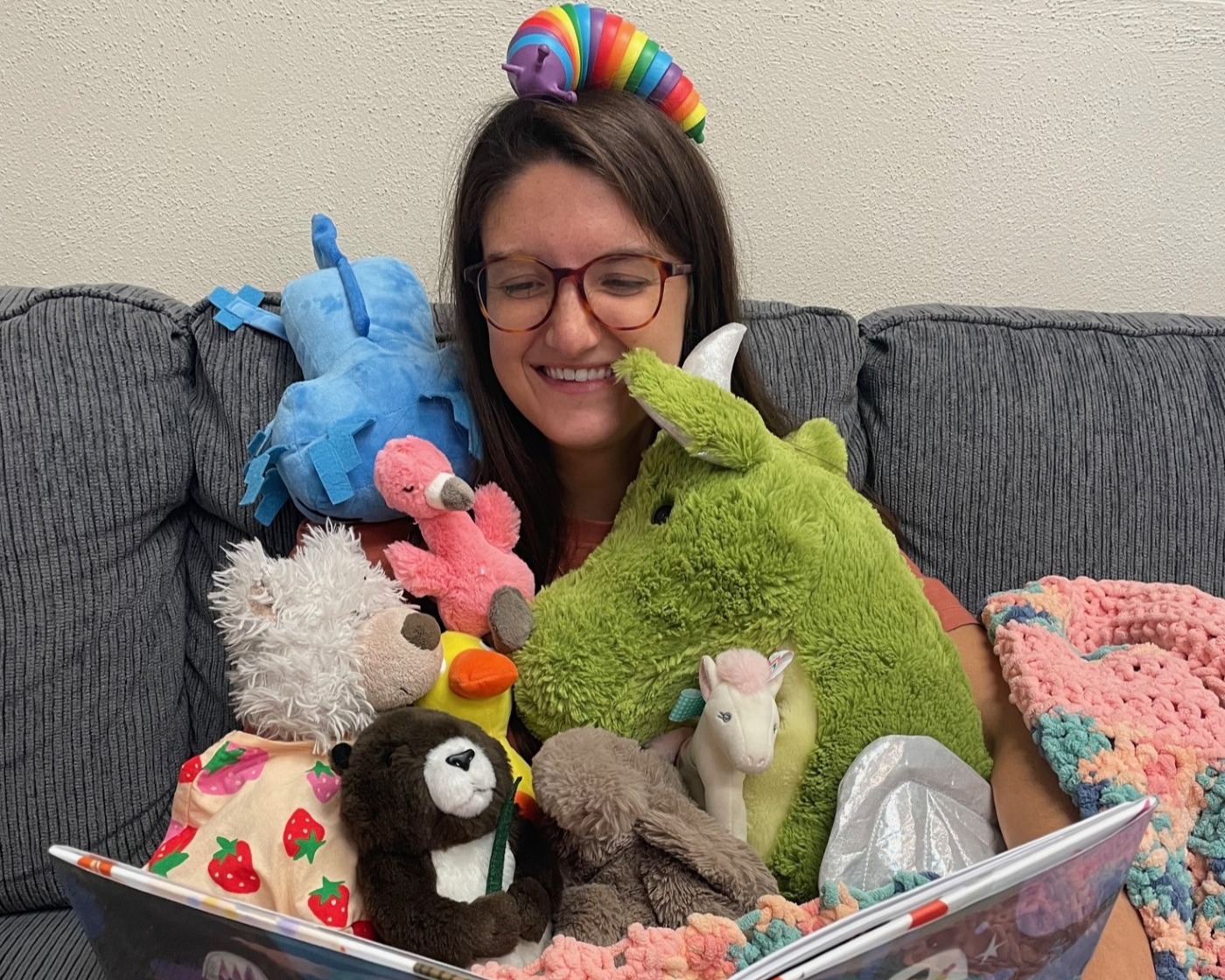 Librarian surrounded by stuffed animals.