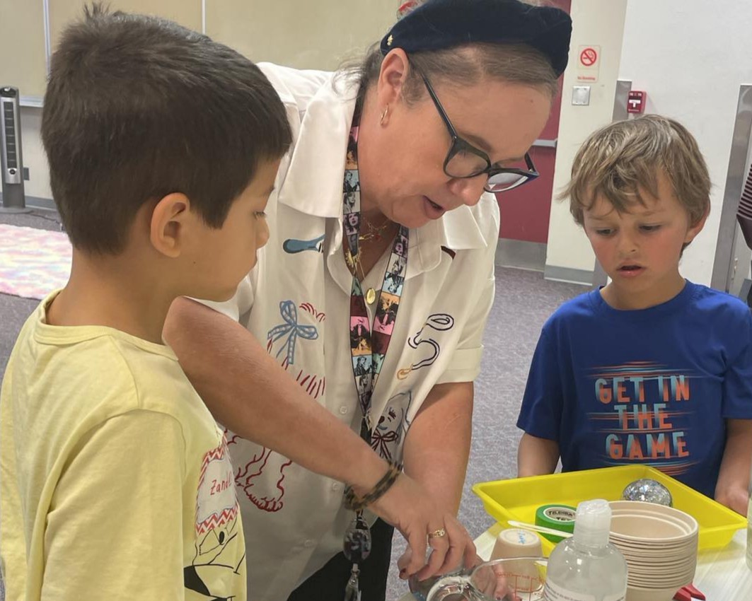 Library staff member demonstrating a science project to two children