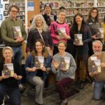 Library staff holding up books