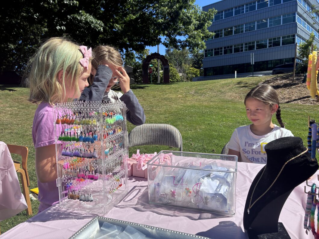 A girl selling her handmade items while another child looks on