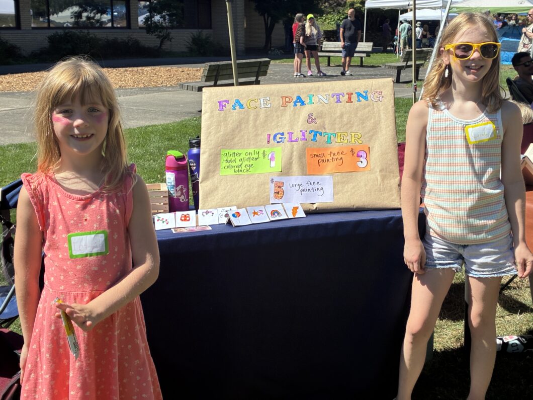 2 girls standing in front of their Craft Fair table