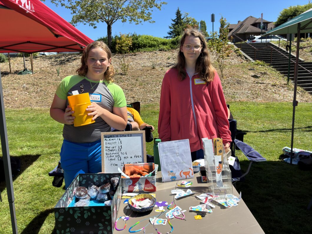 Two children standing behind their Craft Fair table