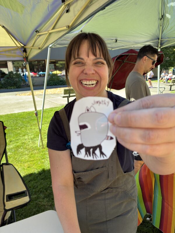 Woman holding up a sticker with a raccoon on it