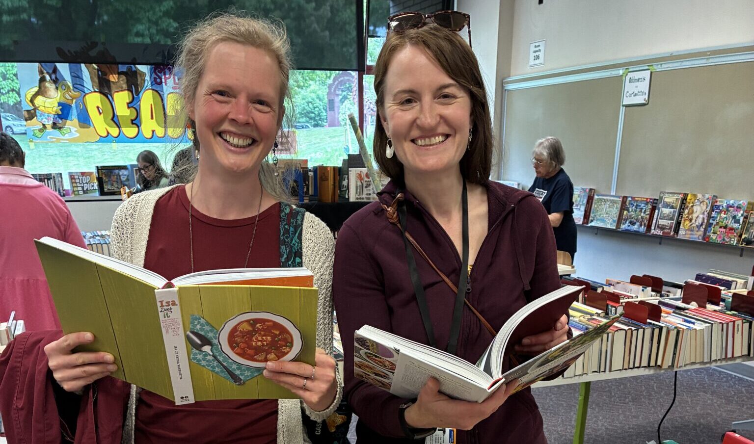 Two smiling women looking at books