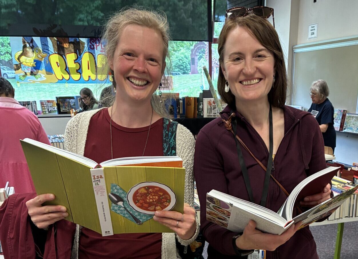 Two smiling women looking at books