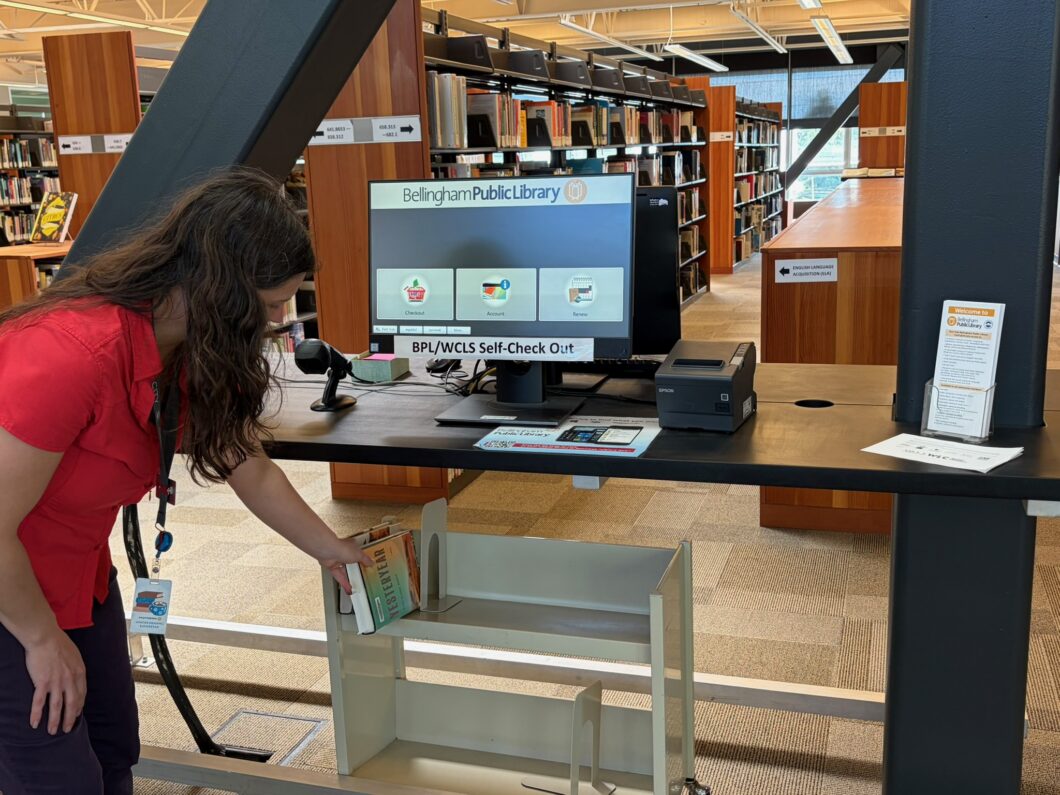 Person picking up book from holds shelf at BTC